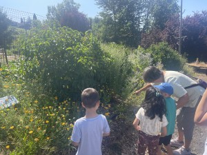 Garden1 kids with an adult in front of a bushes